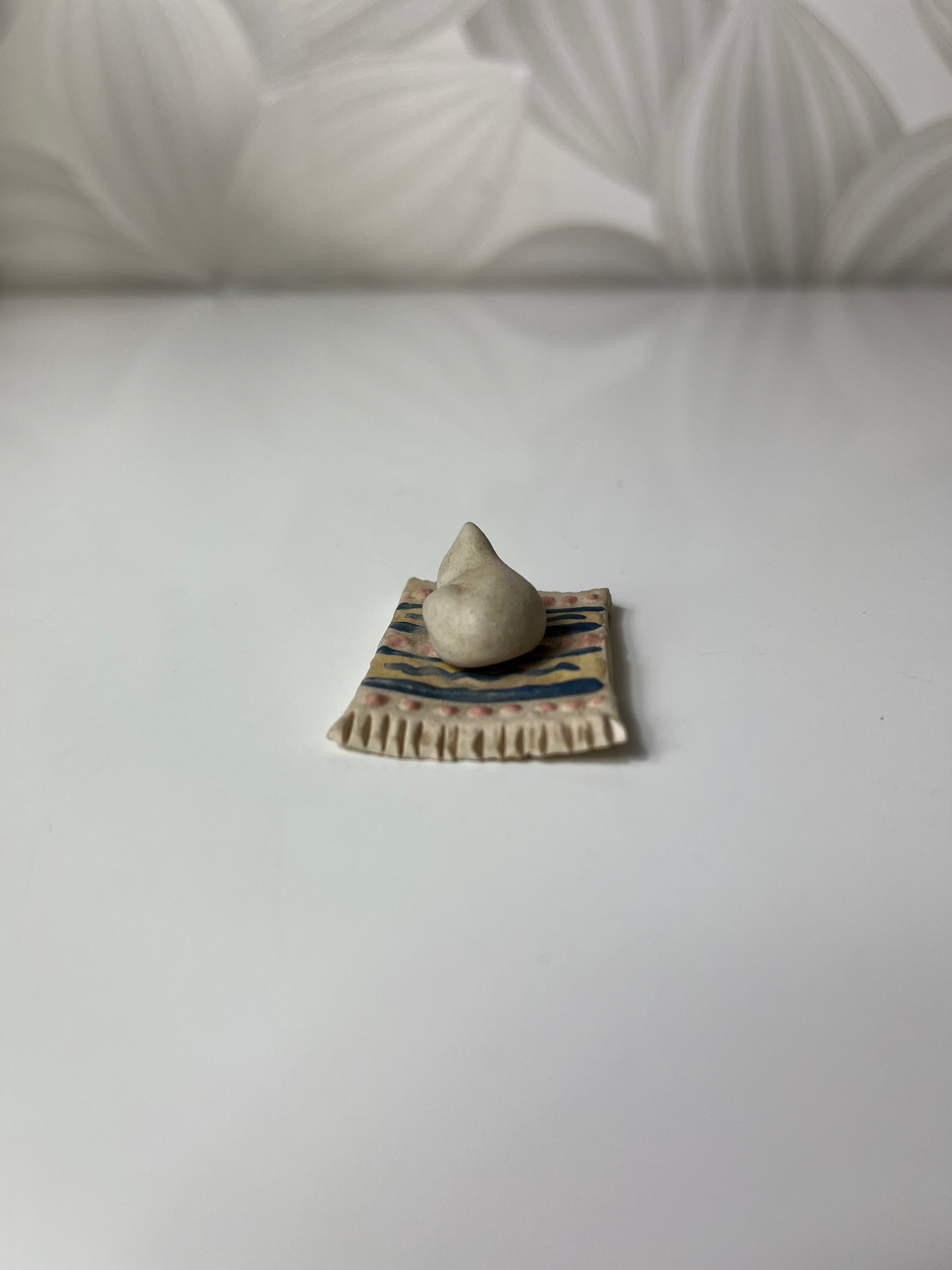 Mažas keramikinis katinas ant kilimėlio