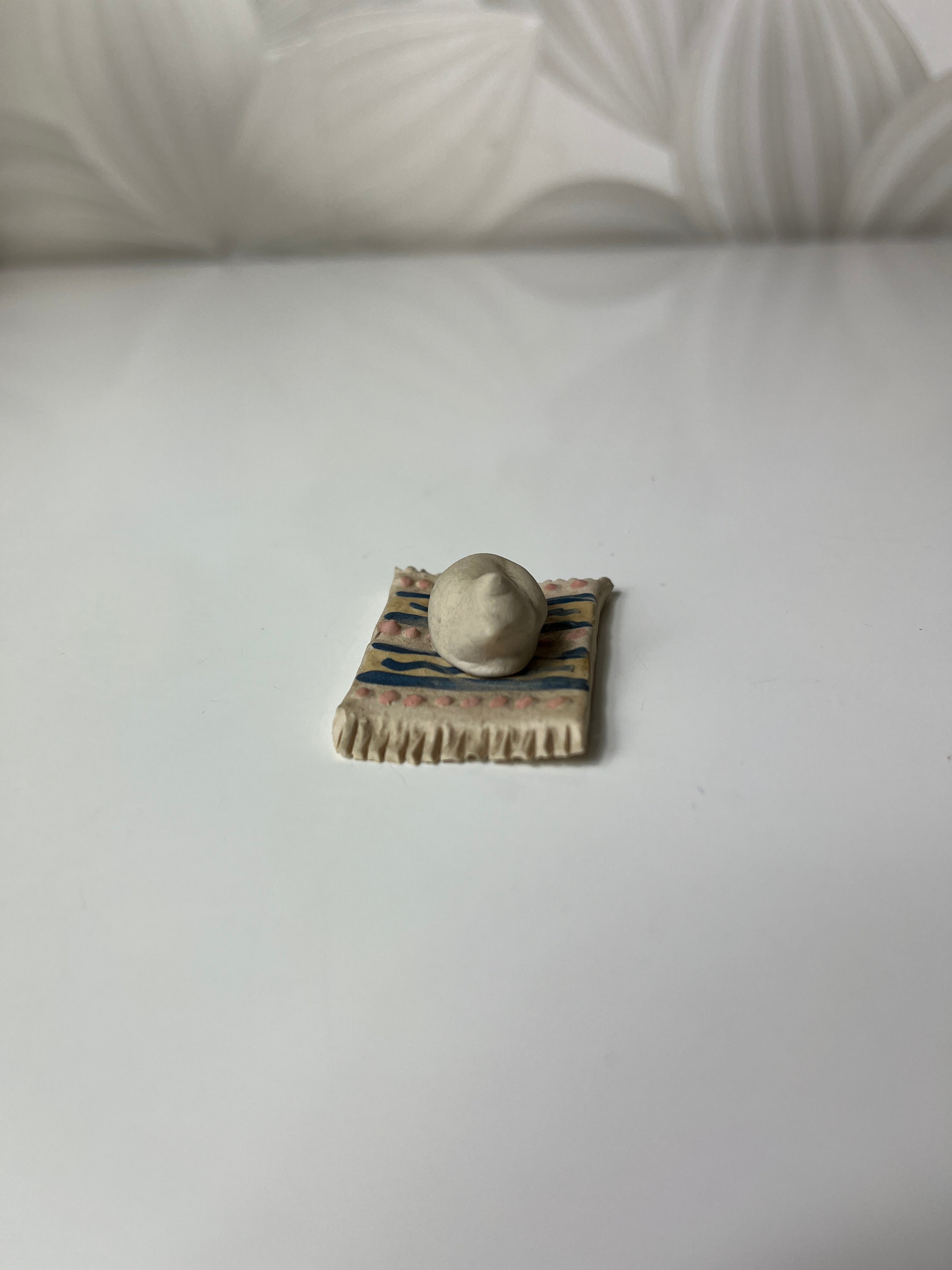 Mažas keramikinis katinas ant kilimėlio